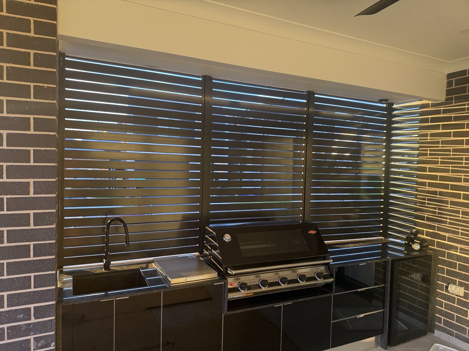 Black horizontal slat screening around an outdoor kitchen